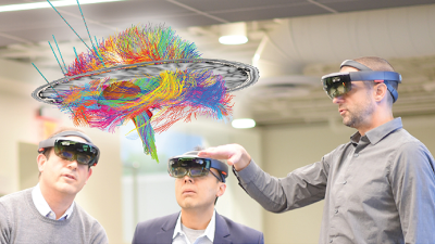 Dr. McIntyre, Dr. Sheth, and Dr. Pouratian look at a brain model while wearing Hololens augmented reality headsets.